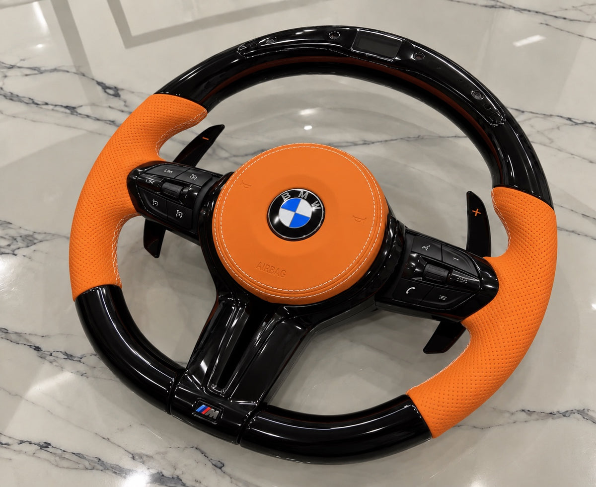 BMW orange leather gloss black LED steering wheel resting on marble
